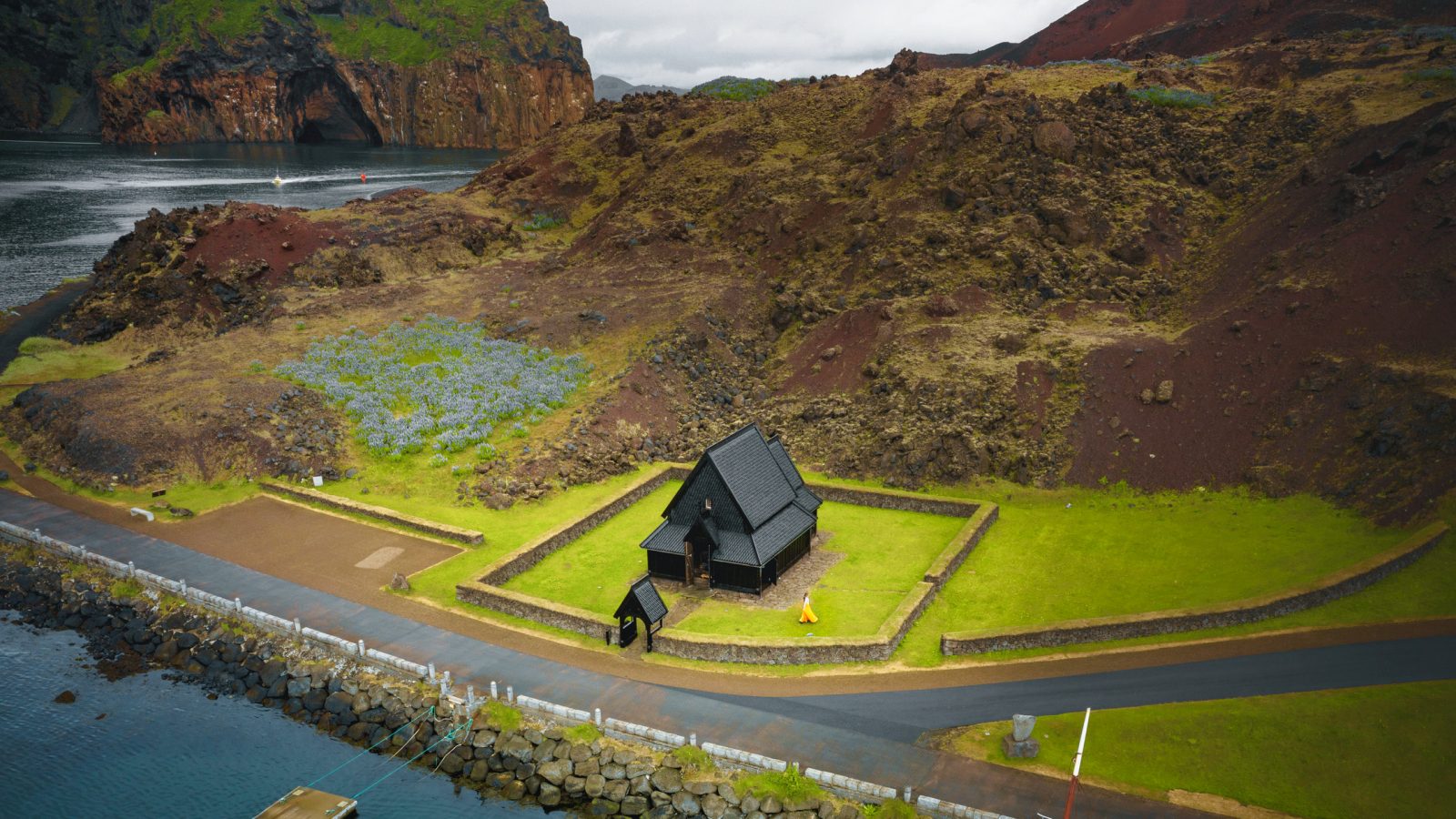 a view from above of the Heimaey stave church, the harbor, and the surrounding volcanic landscape