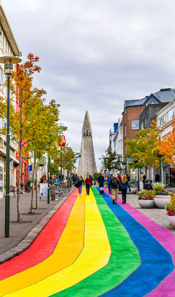 People walking the rainbow painted street in Reykjavik with the church at the end/