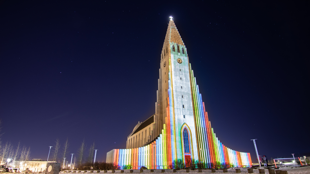 Hallgrimskirkja church lit up with colorful lights during the Winter Lights Festival, one of the best times to visit Iceland.
