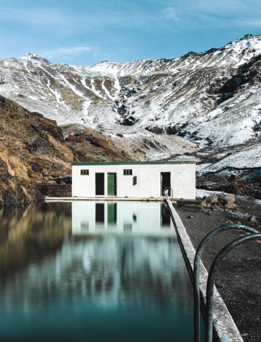 Iceland weather in December brings snow that covers the landscape surrounding the Seljavallalaug swimming pool