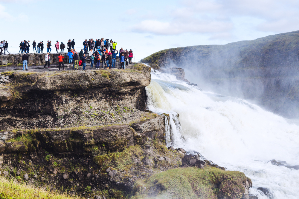 a group of tourists on a tour at gulfs waterfall