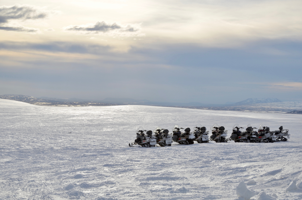 a lineup of snowmobiles at sunset on an ice glacier