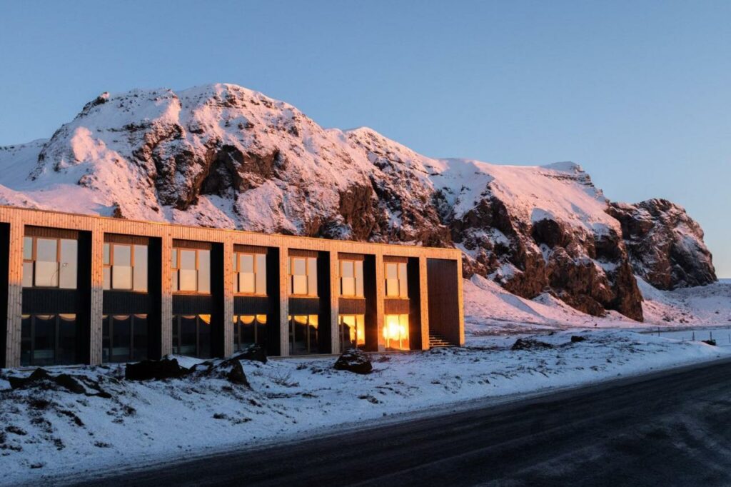 Hótel Kría with a snowy cliff side behind it during sunset, one of the best places to stay in South Iceland.