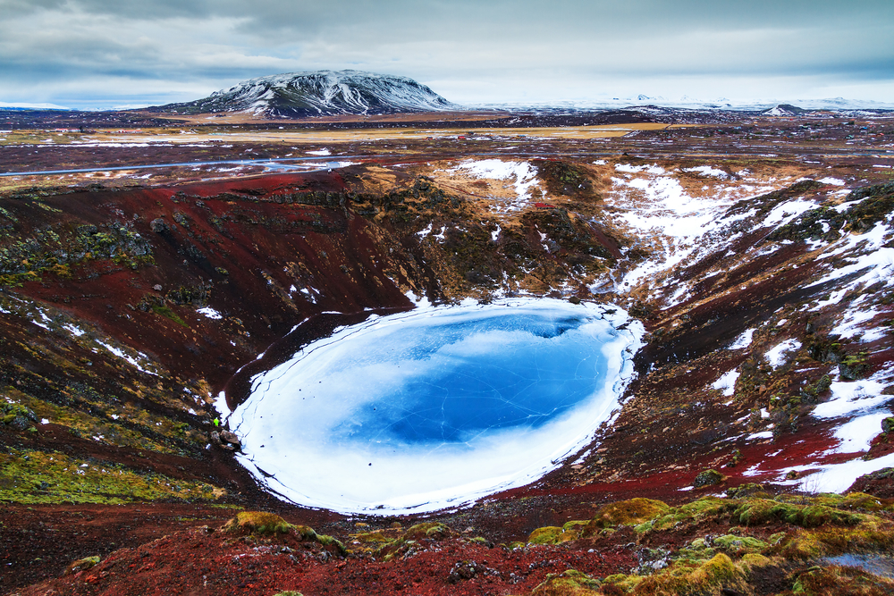 A crater in Iceland with clear blue water and ice