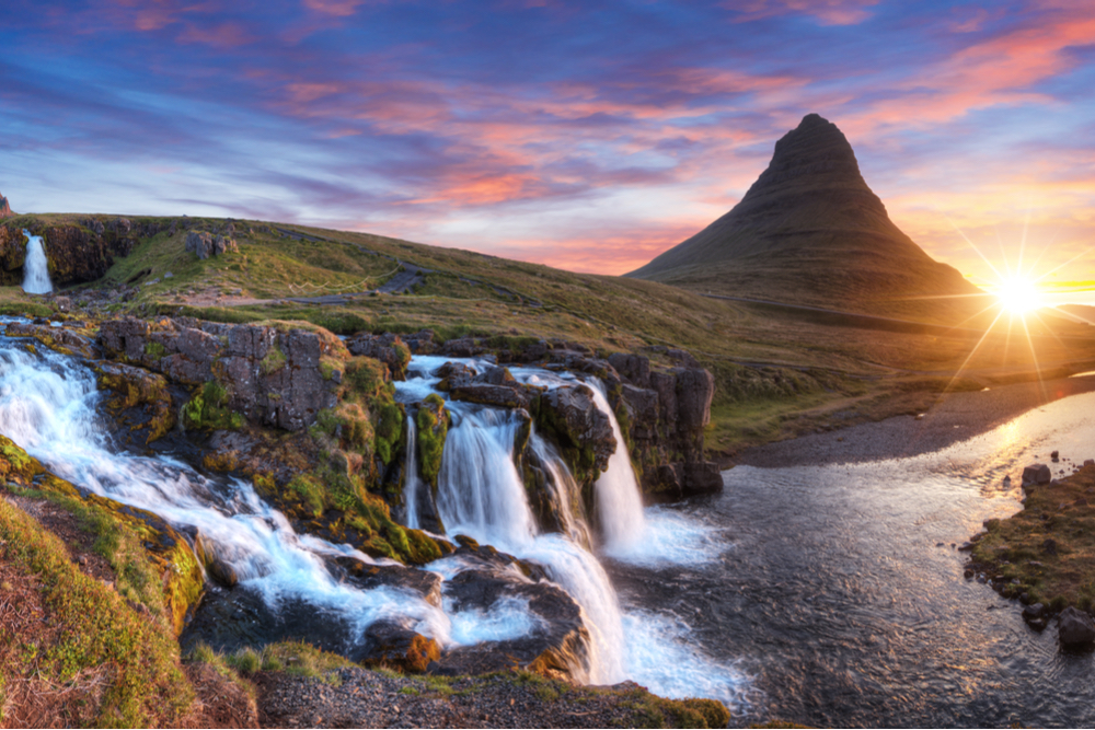 Sunset over a cascading waterfall near Kirkjufell mountain in Iceland 