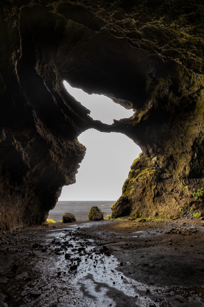 South Iceland view looking out of the Yoda Cave with muddy ground.