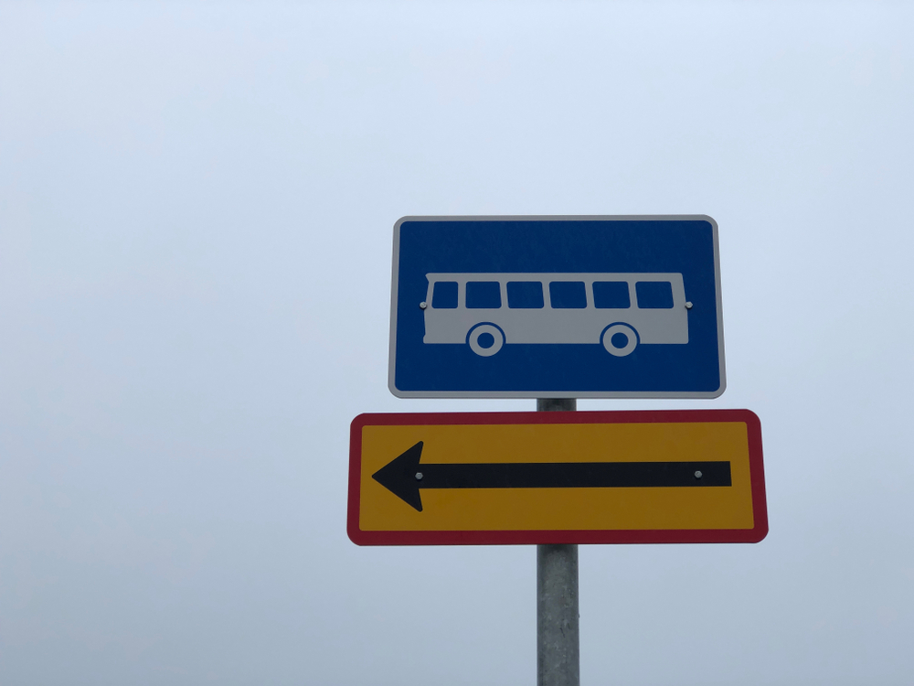 A sign in Iceland with a bus and an arrow pointing to the left. 