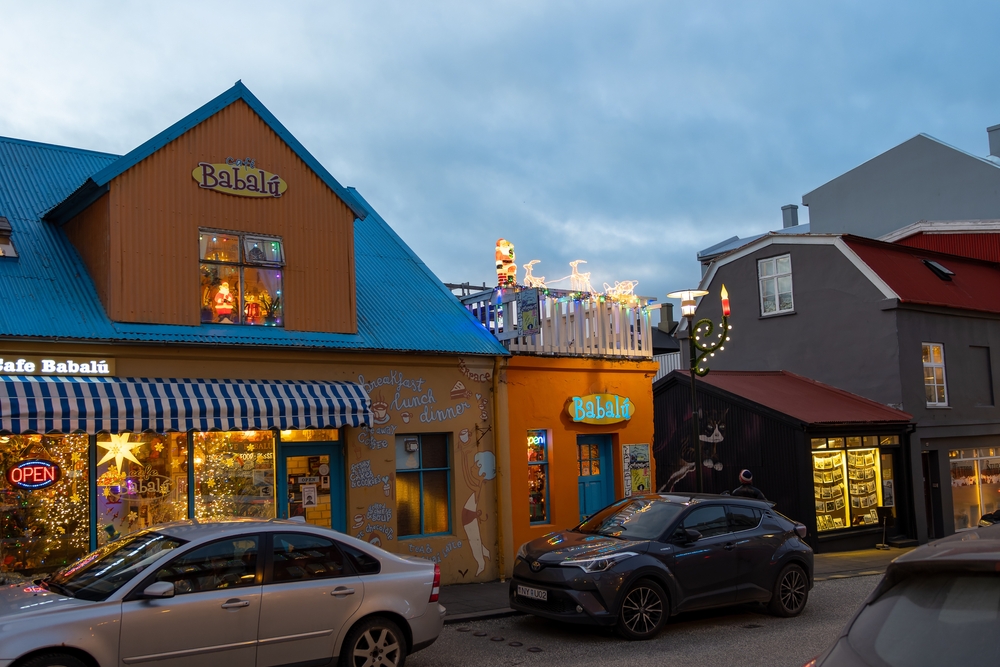 The exterior of Cafe Babalu in Iceland. The building is orange with writing on the outside and cars are packed on the street, 