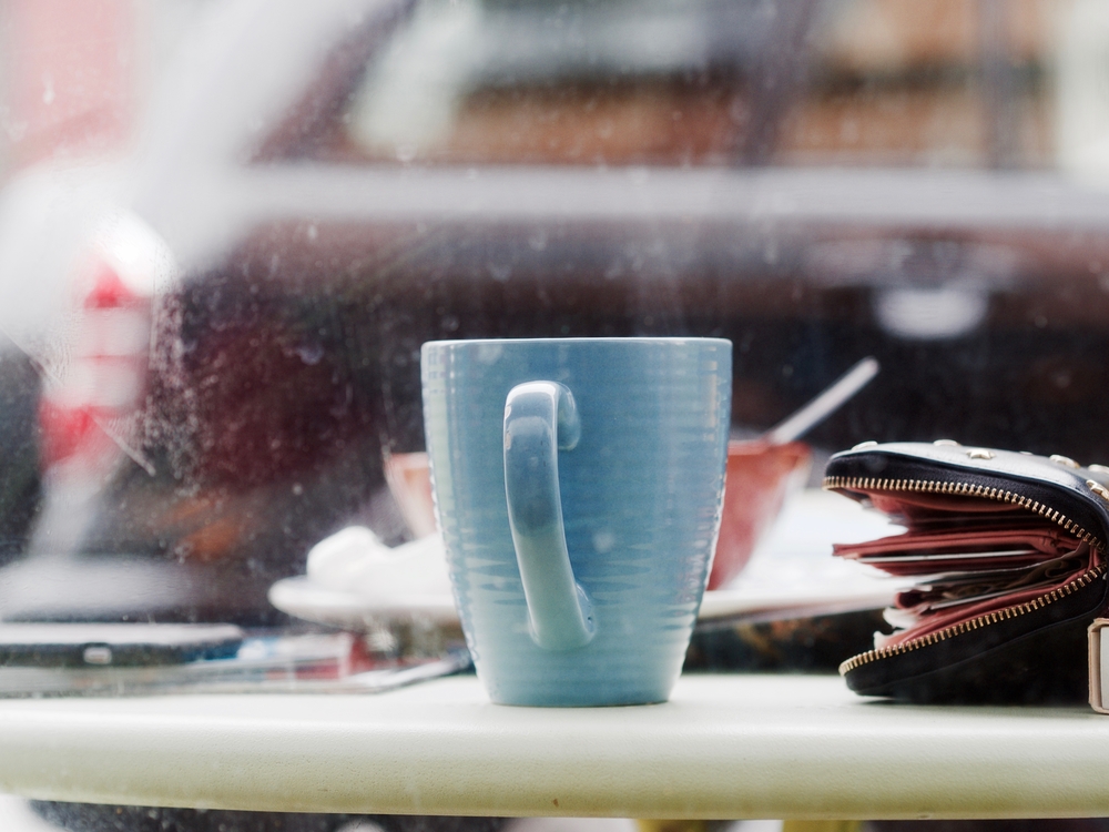 A blue cup on a table with a wallet next to it. 