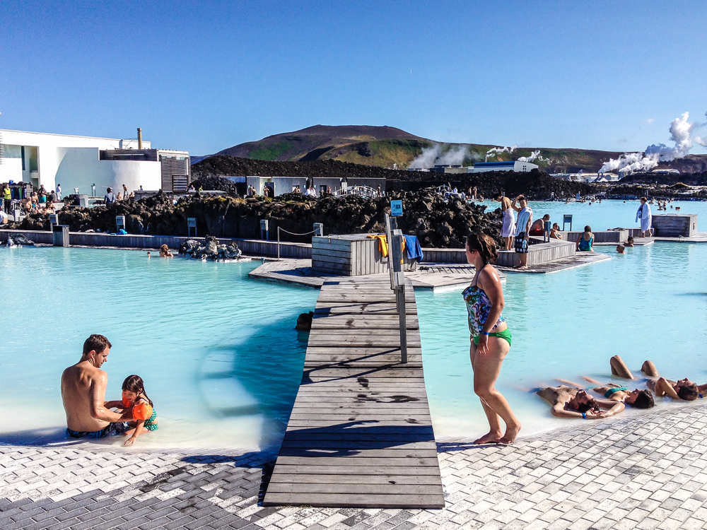 Blue Lagoon iceland with a father and daughter in the water and a women waking past. 