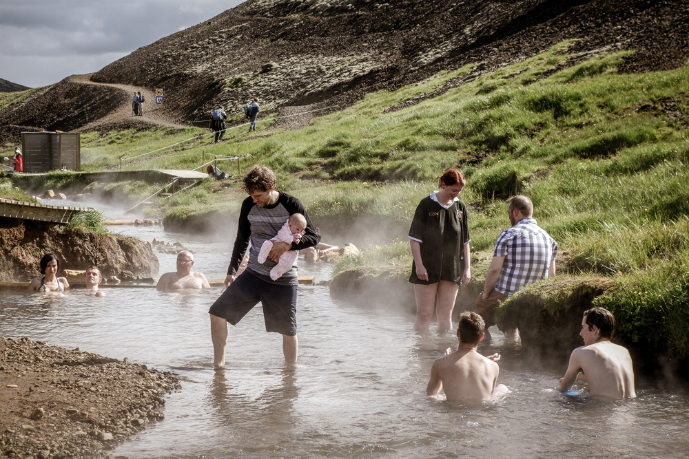 : A father with his baby in hot thermal river of Reykjadalur, Iceland.