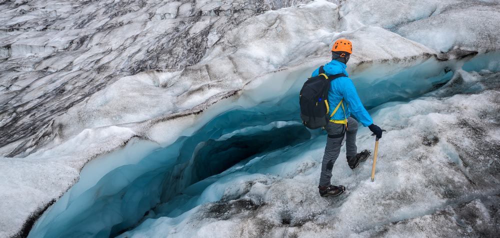 A man uses hiking gear during one of the Iceland south coast tours to walk over the icy slopes of glaciers. 