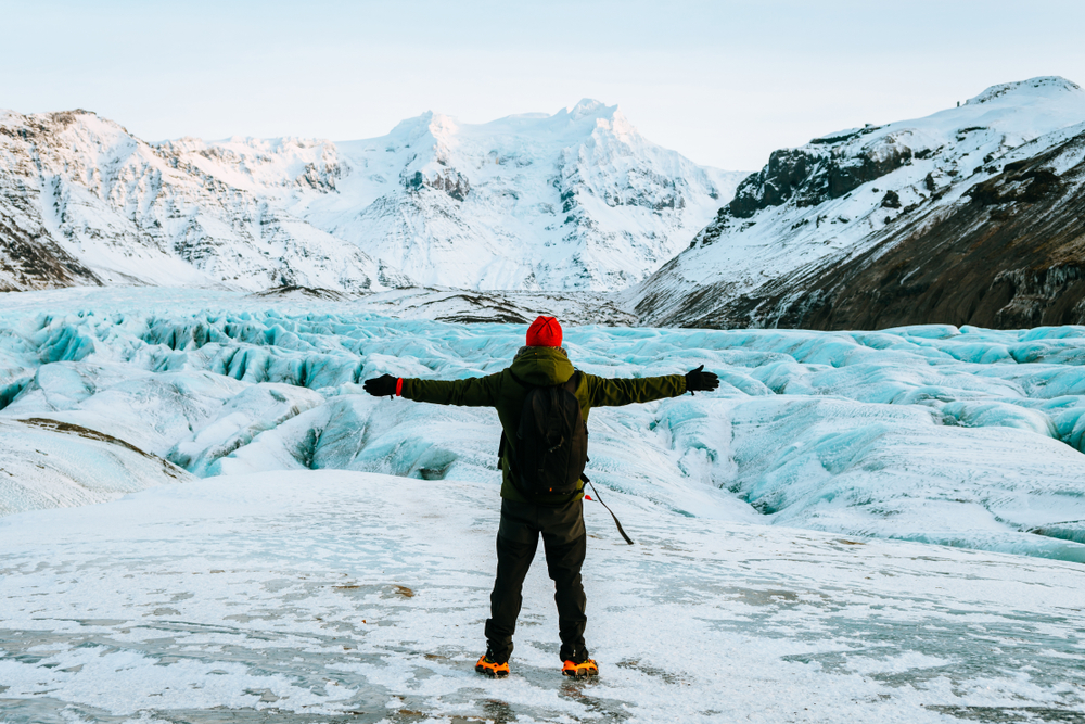 a man standing on ice field with a red hat