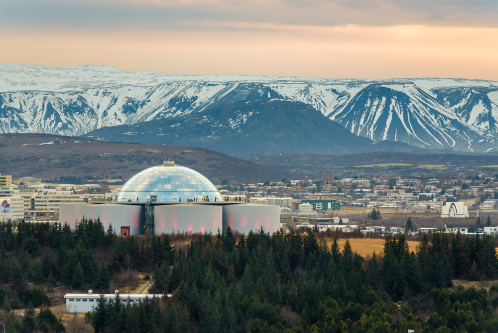 Perlan, landmark building in Reykjavík, the capital of Iceland with snowy mountains in the background, seen from the tower of Hallgrimskirkja church. In an article about museums in Iceland. 