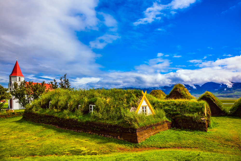 Museum-estate Glaumbaer, Iceland. The concept of the historical and ethnographic tourism. Church bell tower with a peaked red roof in old village. The houses have a turf roof. 