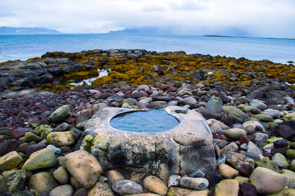 one of the best Reykjavik hot springs, the Kvika foot bath, nestled among some rocks right at the edge of the ocean