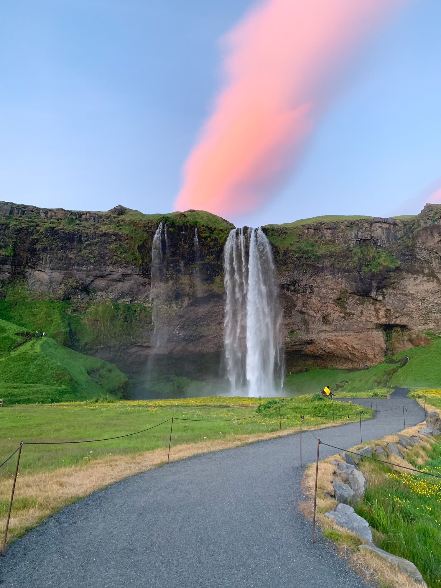 The paved relatively flat walkway up to the Seljalandsfoss waterfall on a sunny day. 