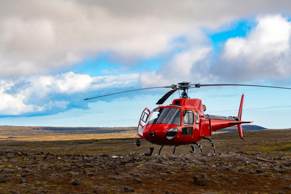 A red helicopter on a mountain summit landing 