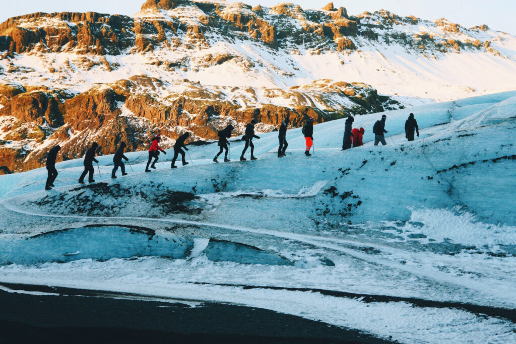 14 people hiking the blue ice of the south Iceland glacier with a snow covered mountain in the background