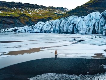 woman standing in front of solheimajokull glacier in iceland
