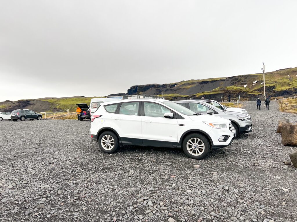 a few cars parked in the gravel lot at the base of Solheimajokull