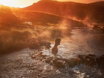 man sitting at hot springs in iceland in july