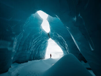 Person stands at the entrance of blue ice caves in iceland