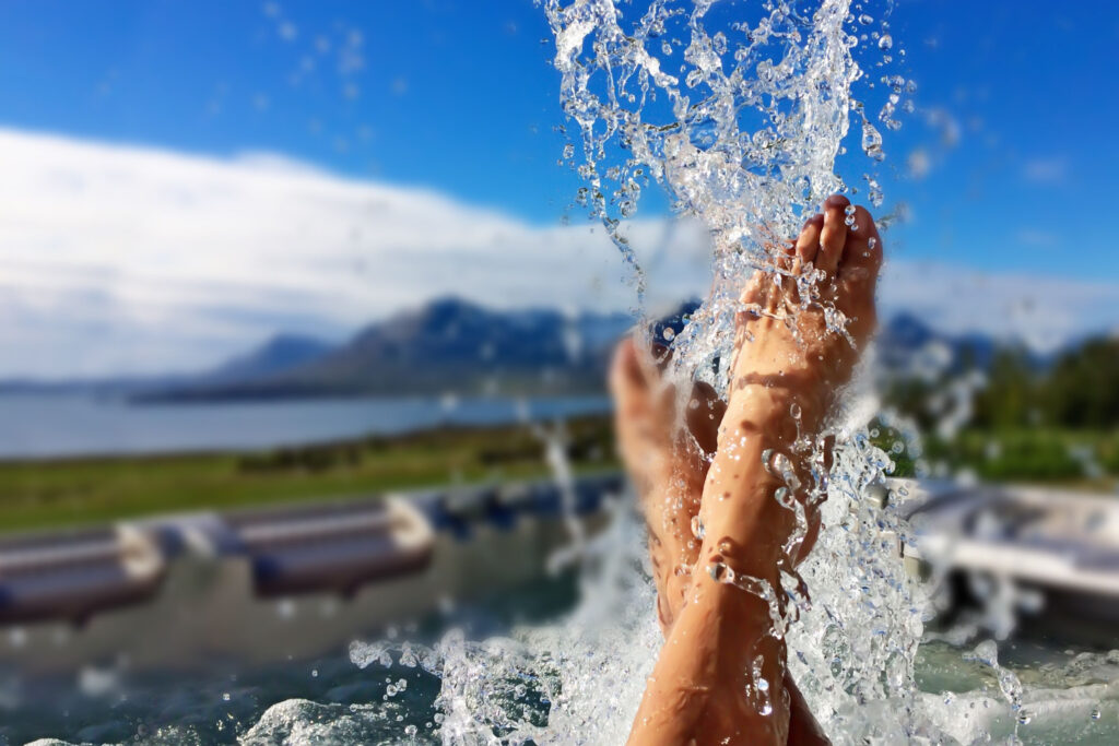 Water splashes from feet at an outdoor pool surrounded by Icelandic mountains and the beach is one of the best things to do in Vik

