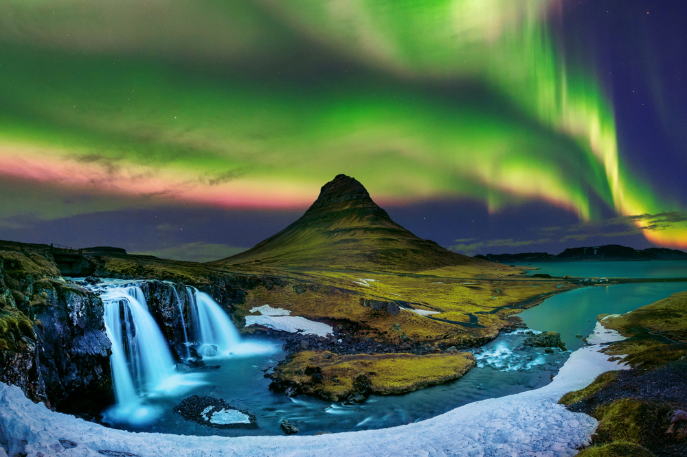 the Northern Lights over the iconic Kirkjufell mountain and the Kirkjufellsfoss waterfalls