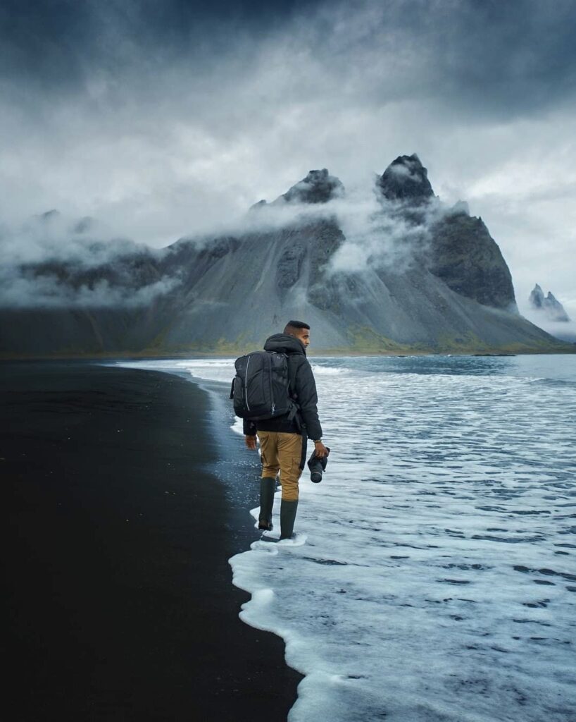 a person walking along the beach at Stokksnes in gloomy weather with clouds covering parts of the mountains