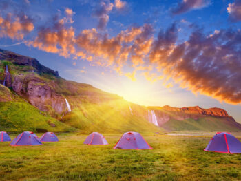 Tents dispersed in open field near Iceland waterfalls