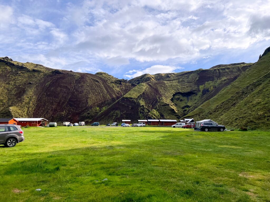 Wide open field with mossy mountains surrounding camper van sites in Iceland