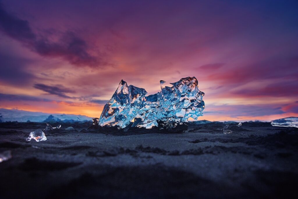 Instagrammable spot in Iceland shows Iceberg chunk sitting on a black sand beach under a purple sky 