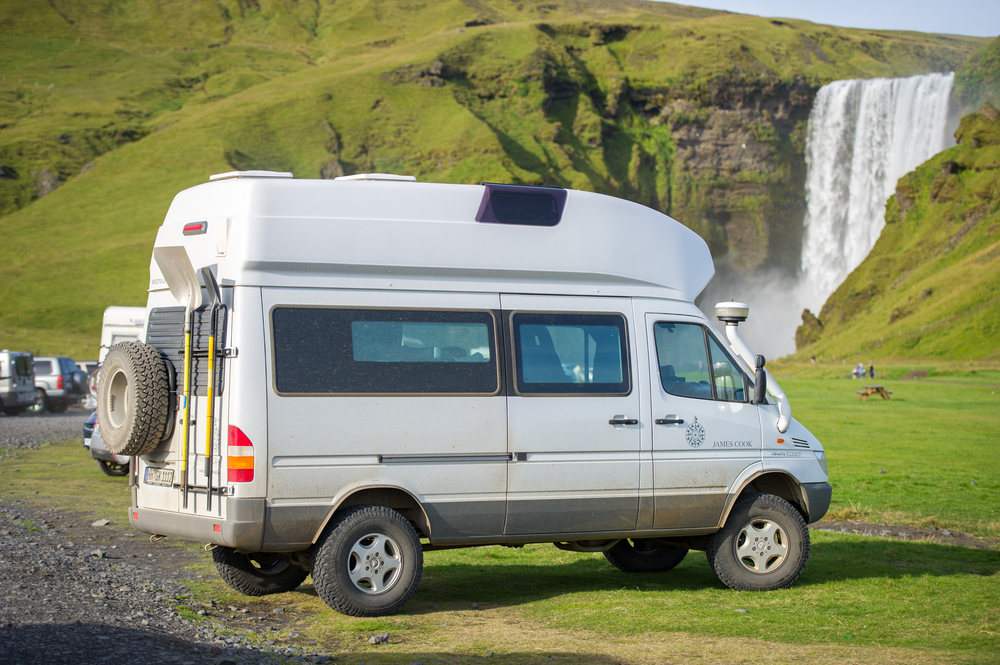 A campervan parked in front of the south Iceland waterfall Skogafoss as a way to visit iceland on a budget and save money