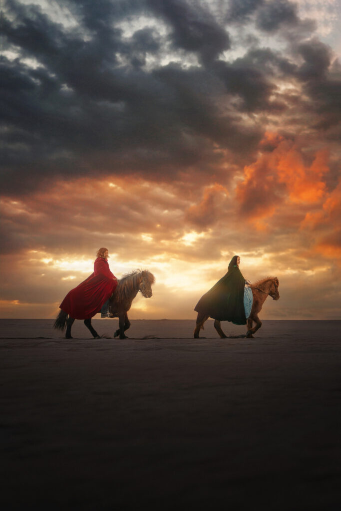 Viking girl and guy on horseback riding tour in Iceland under a glowing sky along the beach