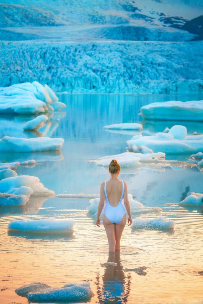 wearing a white bathing suit and standing in the water of the Fjallsarlon Glacier Lagoon
