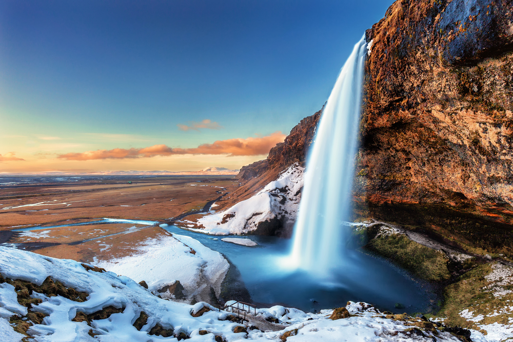Seljalandsfoss in the winter with the surrounding area partially covered in snow and the vast south coast landscape turned brown