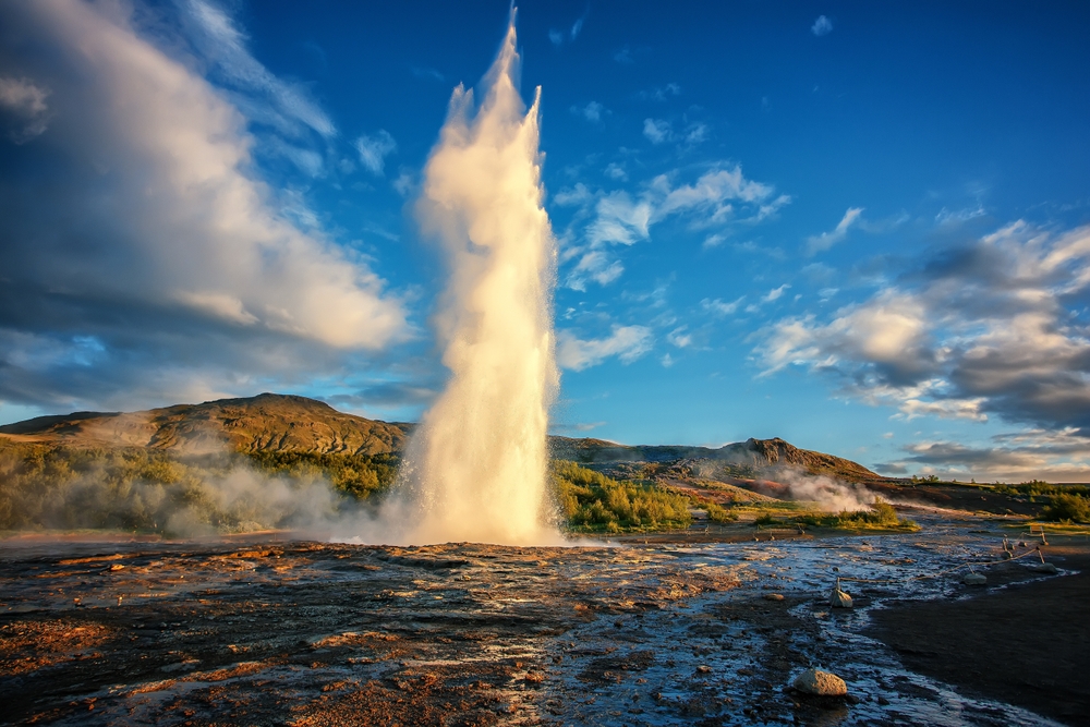 Strokkur geyser shooting into the air during the golden hour.