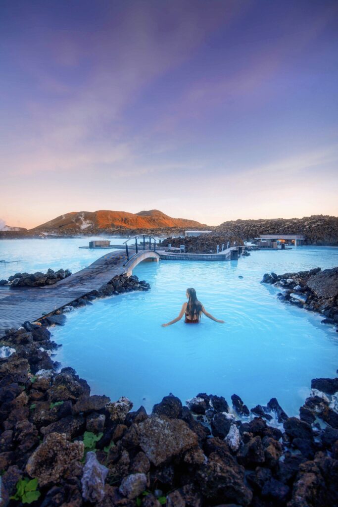 standing in a cove of the Blue Lagoon surrounded by black lava rock
