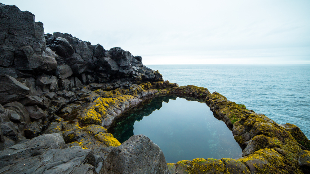 Brimkettil lava pool surrounded by laval rock and the Atlantic Ocean beyond