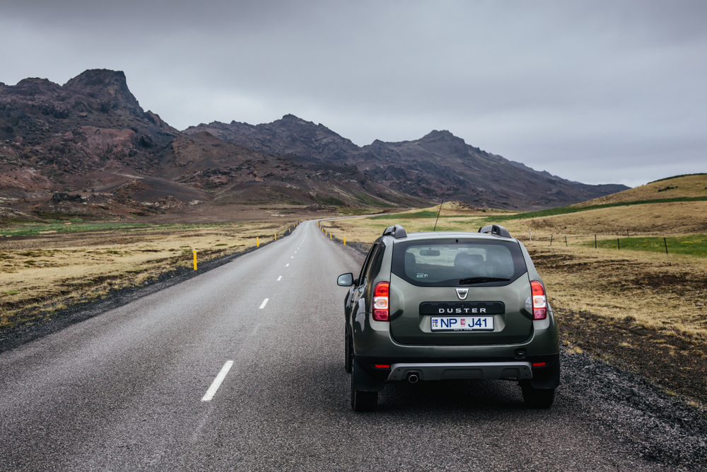 a car driving along the road on the Reykjanes Peninsula with jagged mountains in the background as they embark on their itinerary of the best things to do in Reykjanes Peninsula