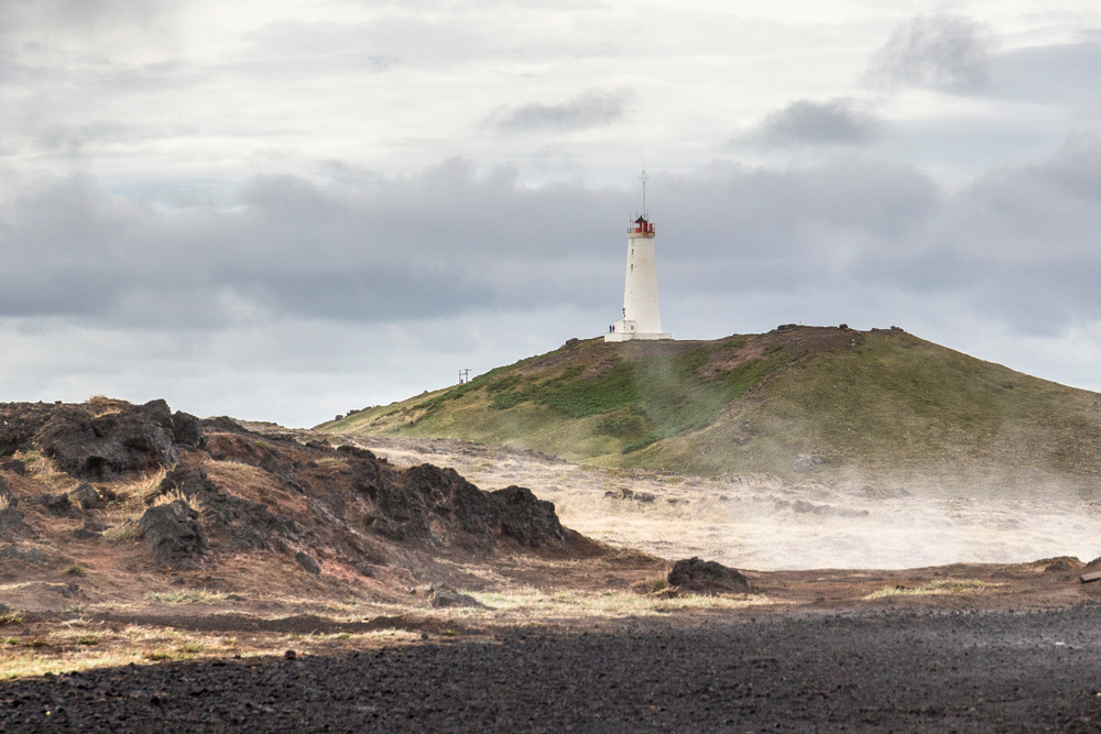 a view of the Reykjanesviti lighthouse from the black sand beach by Gunnuhver hot springs