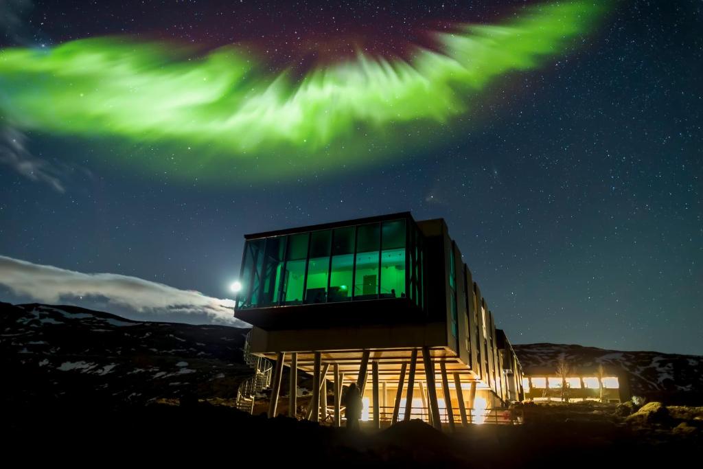 Unusual glass and concrete hotel on silts. It sits on the mountain and the northen lights are behind it.  