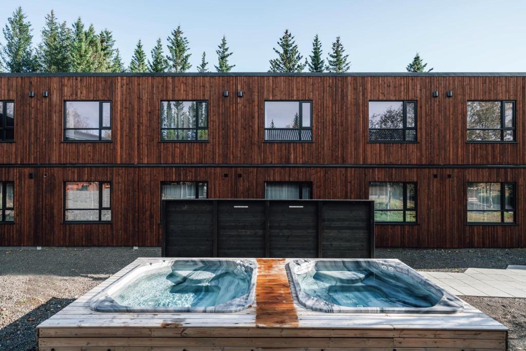 Wooden hotel with two hot tubs in front of it. 