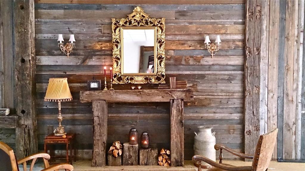 Wooden wall of a hotel with a wooden fireplace, There is an ornate mirror on the wall. 