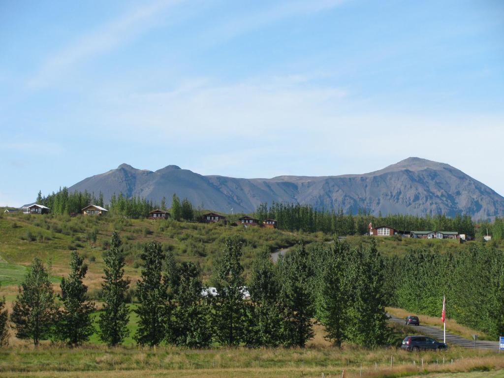 cabins of a hotel on a grass hill with a mountain behind.  The article is about where to stay on the Golden Circle. 