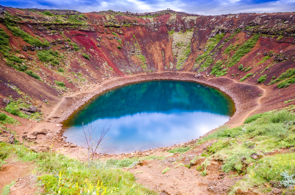 Red volcanic crater of Kerid with a glacier lake at the bottom. The article is about where to tsay on the Golden Circle. 