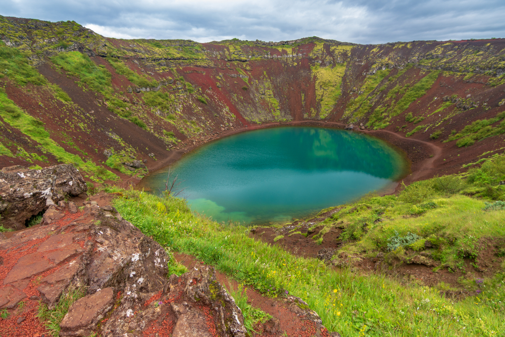View looking down at the Kerid Crater with deep, green water.
