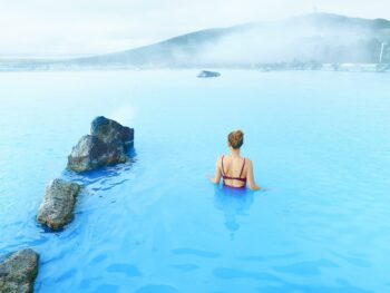 woman standing in myvtan nature baths blue water in iceland wearing a maroon swimsuit