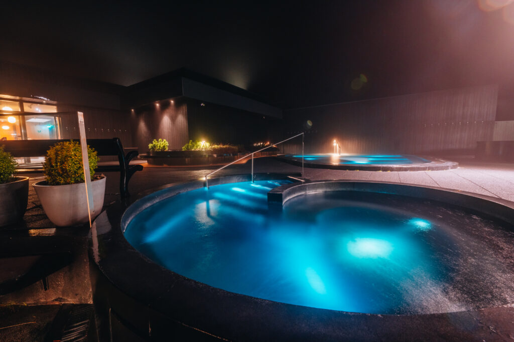 nighttime at Krauma Geothermal Spa with the pools lit up a vibrant blue